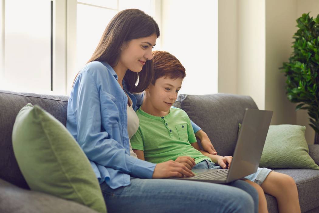 Mother sitting with son browsing the internet on a laptop